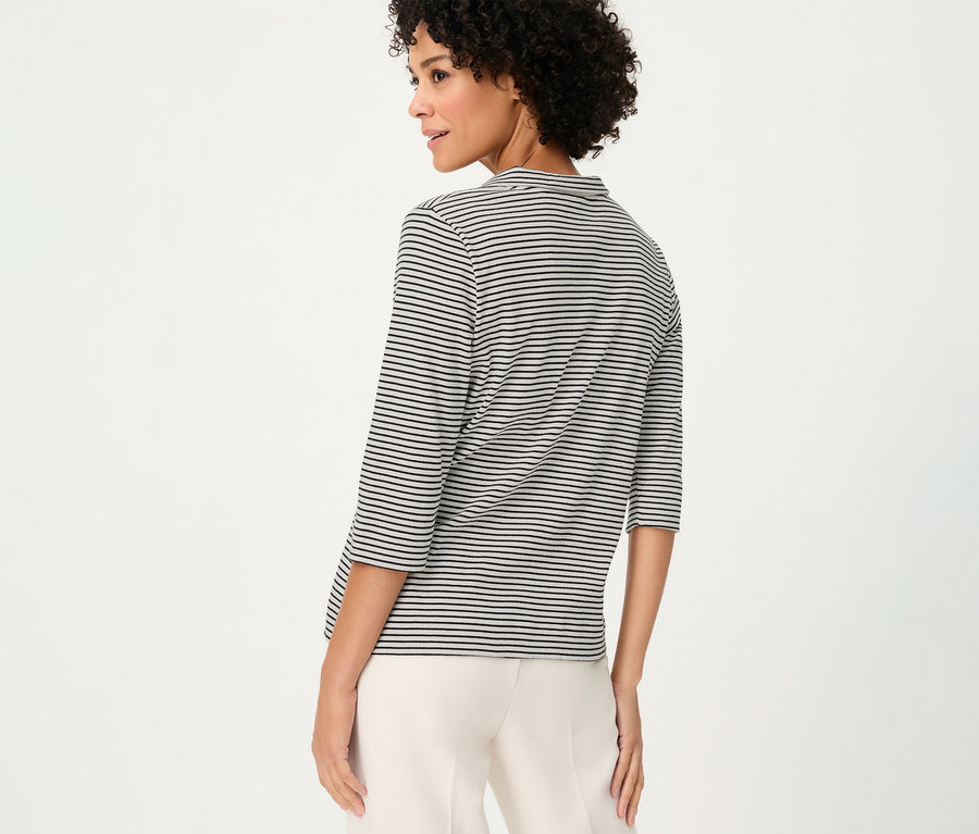 Femme vue de dos portant un polo Olsen rayé et un pantalon beige sur fond blanc.