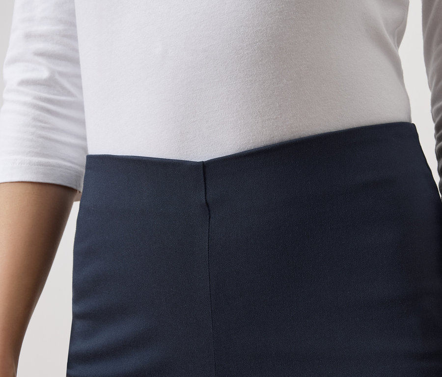 Gros plan d'une personne portant une robe bleu marine et un haut blanc à manches longues.