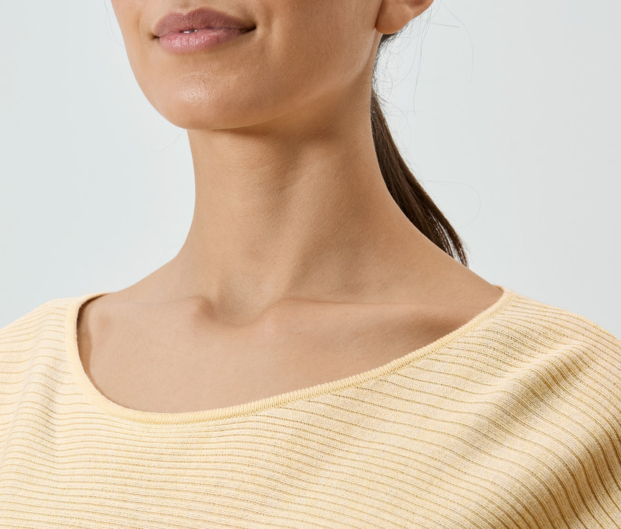 Gros plan d'une femme portant un haut jaune.
