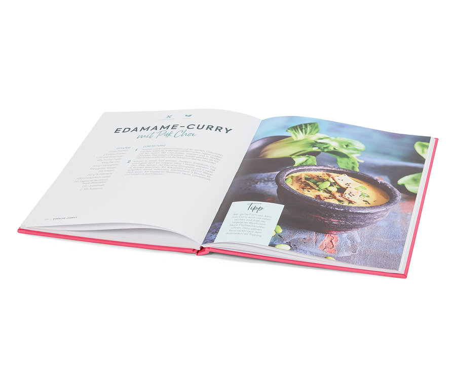 Livre de cuisine ouvert présentant une recette de curry d'edamames et de pak-choi, à côté d'une assiette contenant le plat préparé.