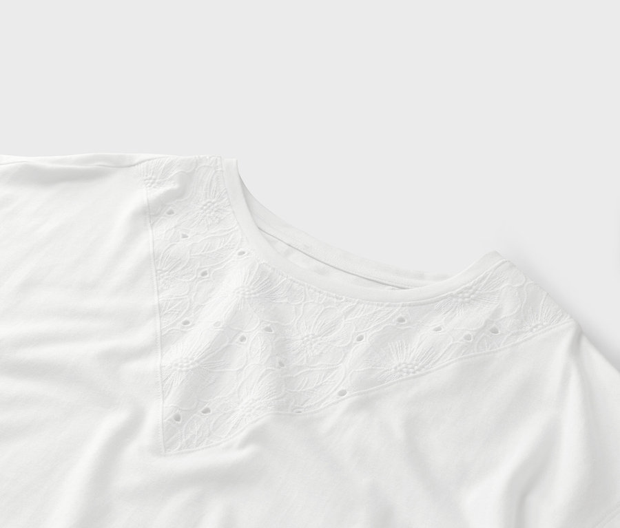 Gros plan sur un t-shirt blanc avec broderie ajourée en V.