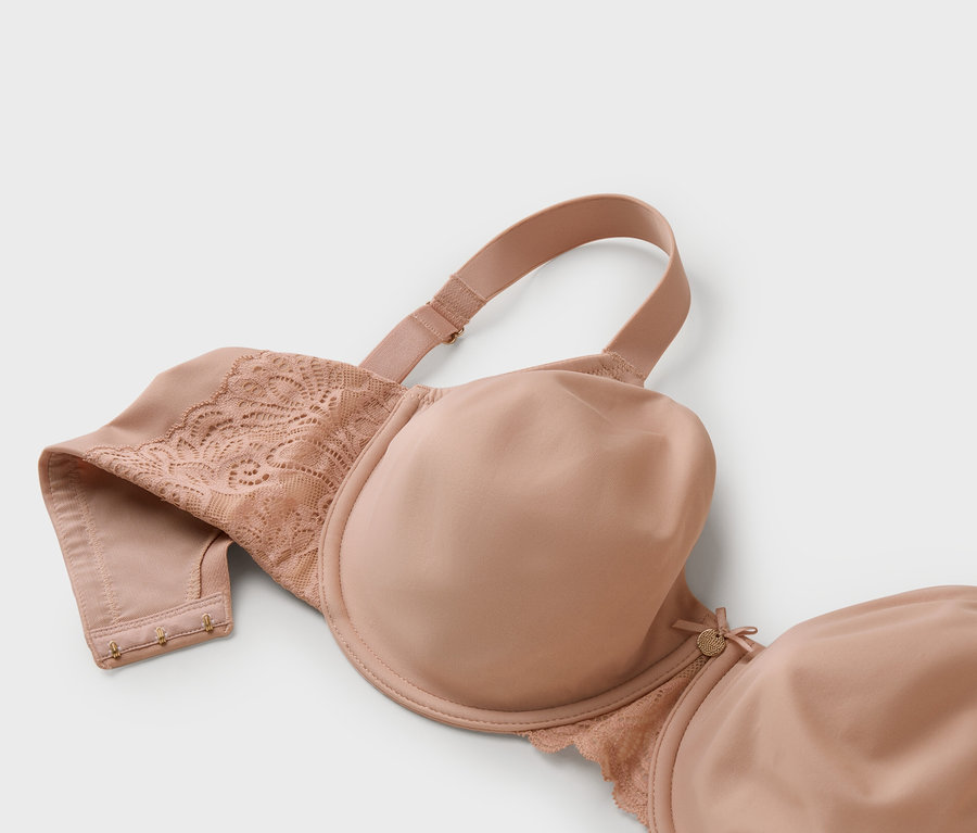 Gros plan d'un soutien-gorge nude avec de la dentelle sur fond gris.