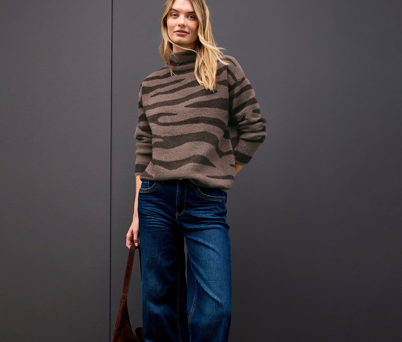 Femme portant un pull jacquard Street One, un jean et un sac à main marron.