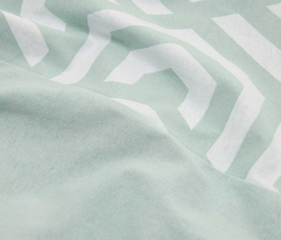 Gros plan d'un tissu vert menthe avec un motif en zigzag blanc.