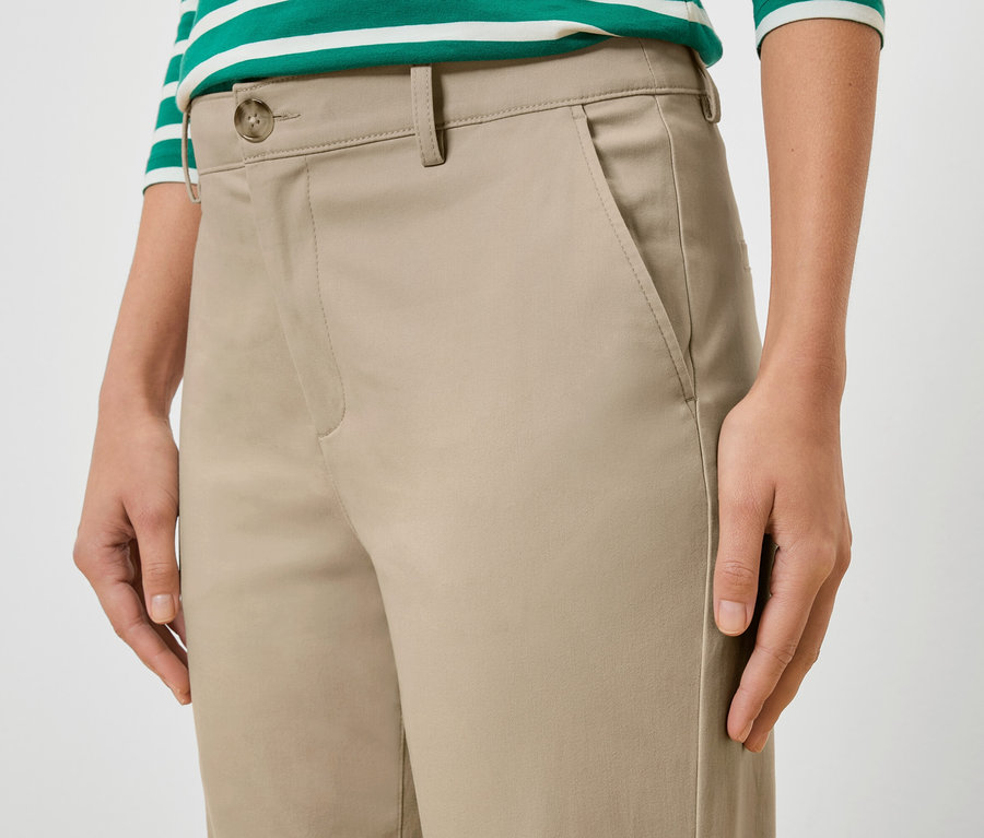 Gros plan d'une femme portant un pantalon beige et un haut rayé vert et blanc.