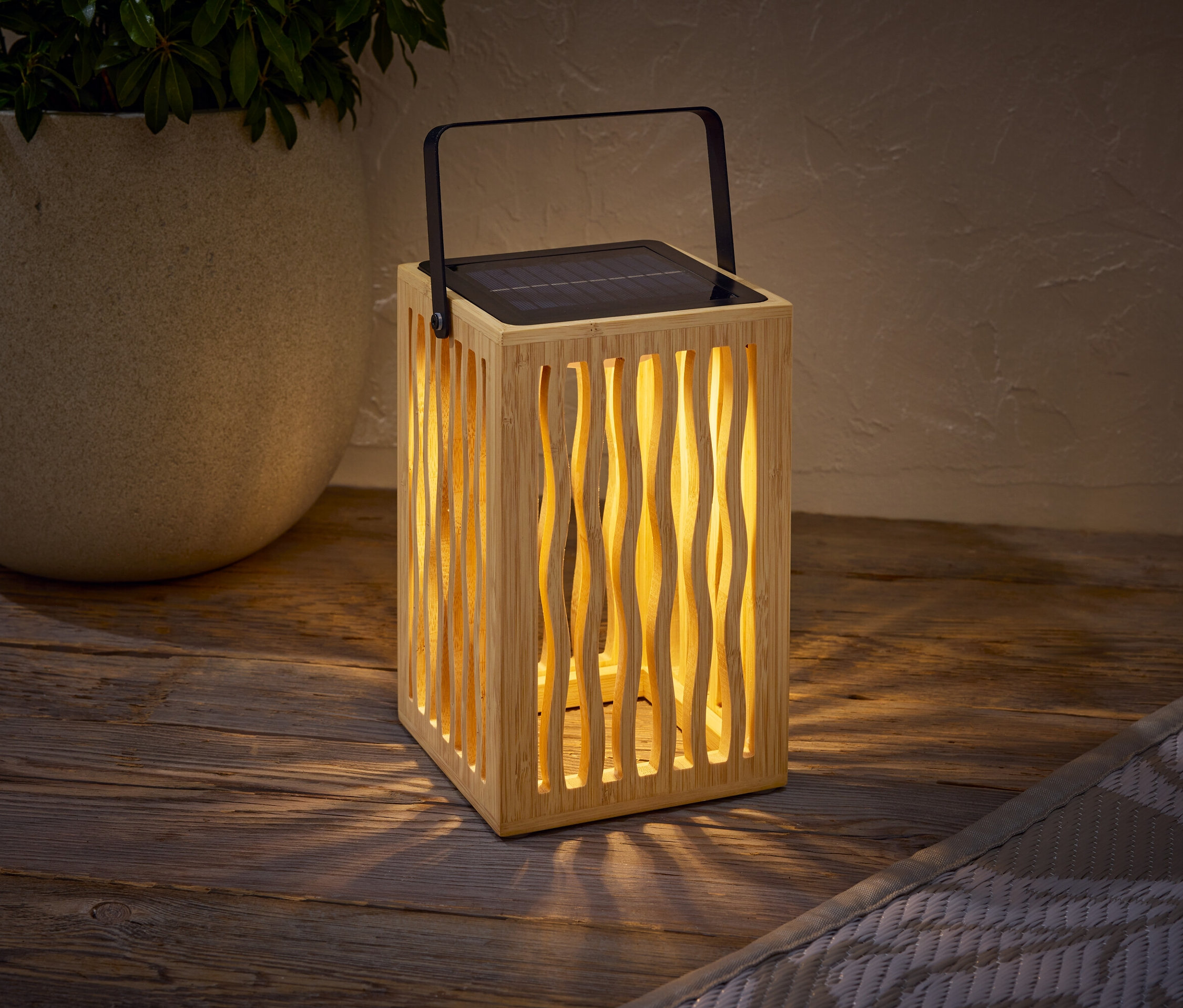 Une lampe solaire en bois avec une poignée noire est posée sur une table en bois à côté d'un pot de fleur contenant une plante.