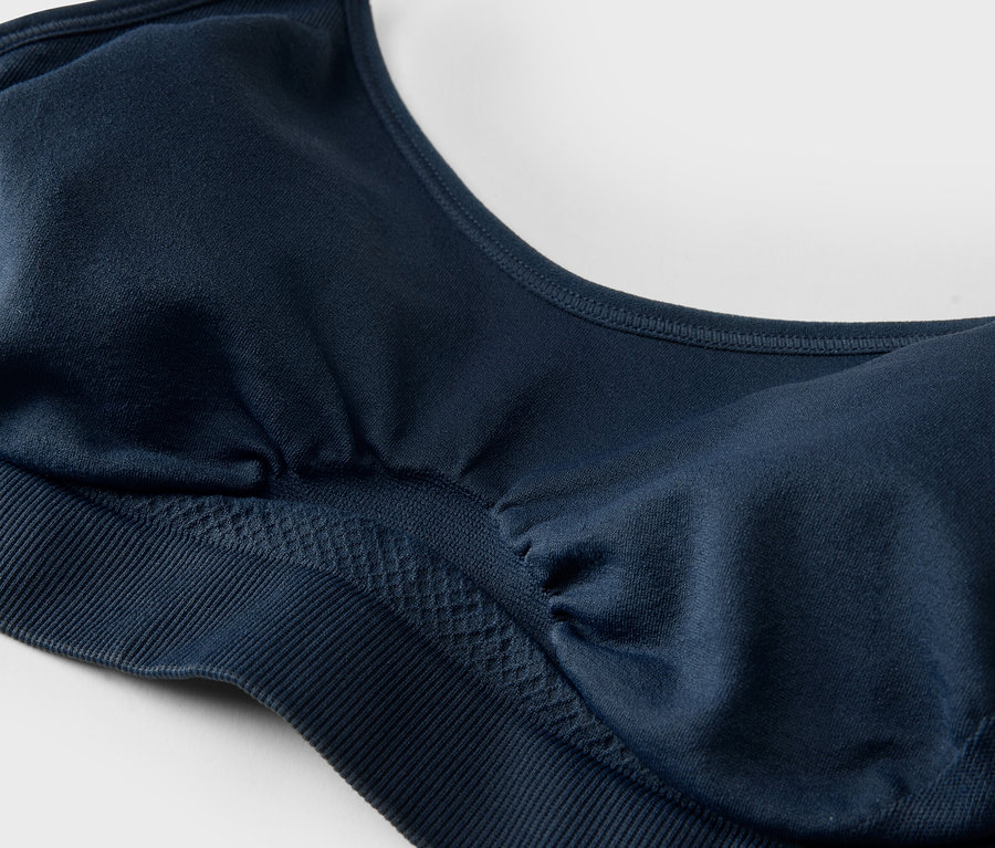 Gros plan d'un soutien-gorge de sport bleu marine avec des bonnets moulés et une large bande sous la poitrine.