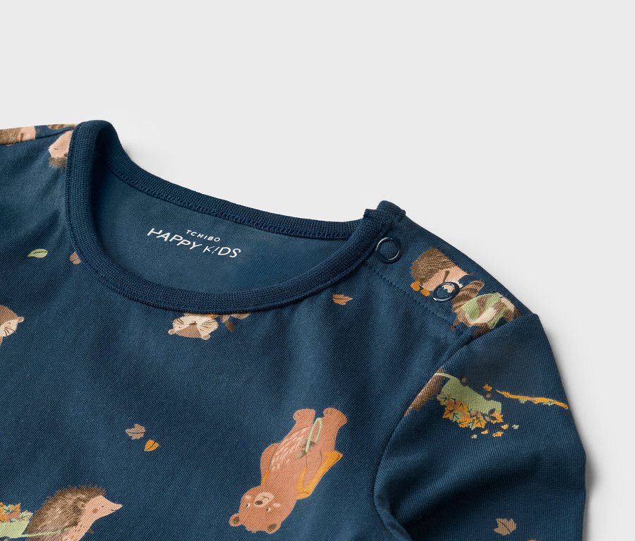 Gros plan sur un t-shirt bleu marine avec un motif animalier et deux boutons sur l'épaule.