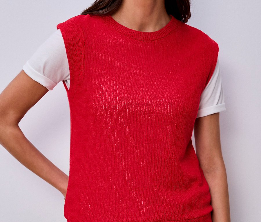 Femme portant une chemise Street One sous un gilet rouge en tricot et un jean, la main dans la poche.