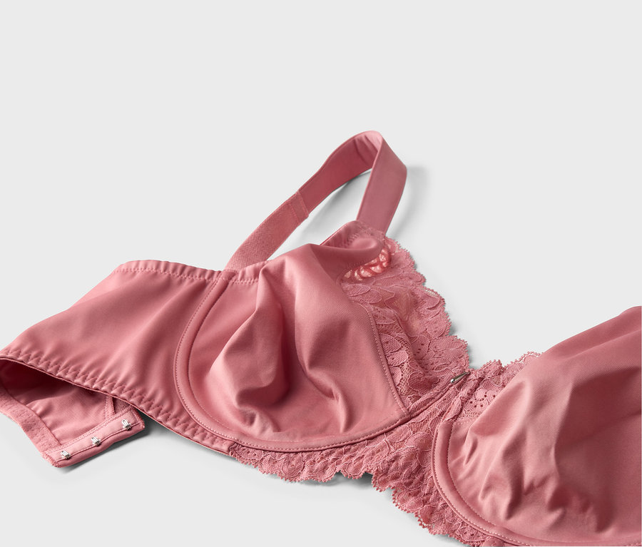 Gros plan d'un soutien-gorge rose avec de la dentelle et des bretelles réglables sur fond blanc.