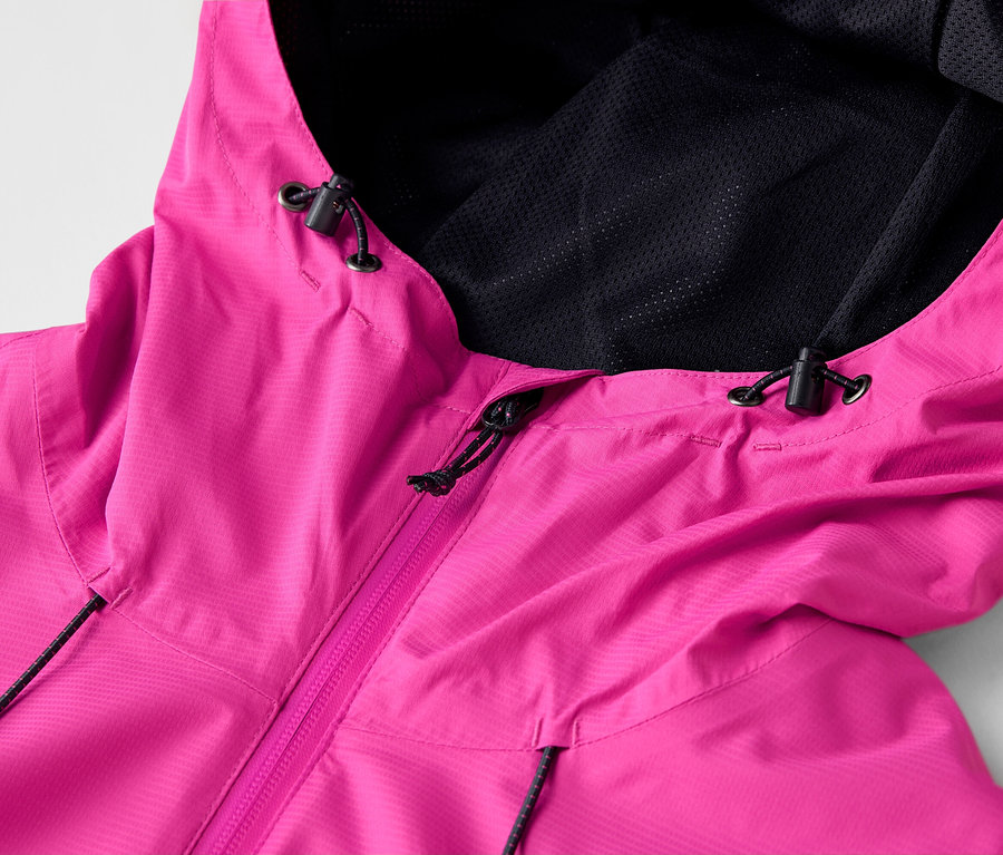 Gros plan d'un imperméable rose avec capuche et doublure en maille noire.