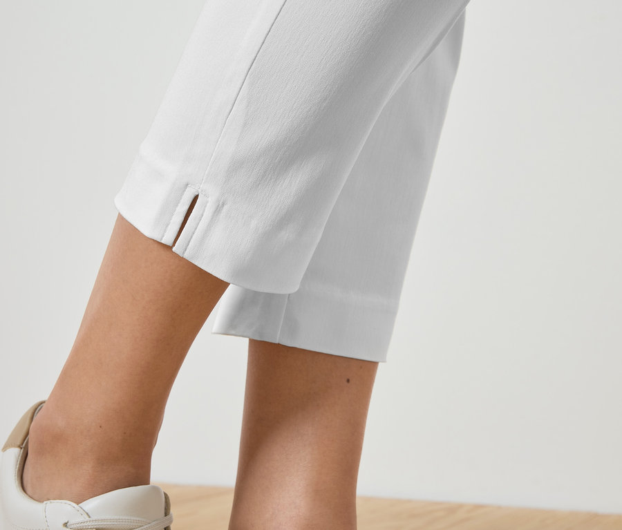 Gros plan sur les jambes d'une personne portant un pantalon blanc et des baskets assorties.