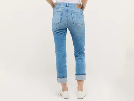 Hanches et jambes d'une femme portant un jean bleu clair et des baskets blanches, vue de dos.