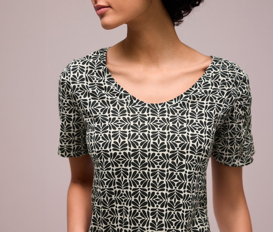 Une femme porte un T-shirt Street One à motif de feuilles noires et col en V.