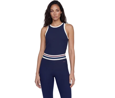 Femme debout portant un débardeur côtelé bleu marine avec des liserés blancs et un legging côtelé assorti avec une ceinture rayée et le logo FILA.