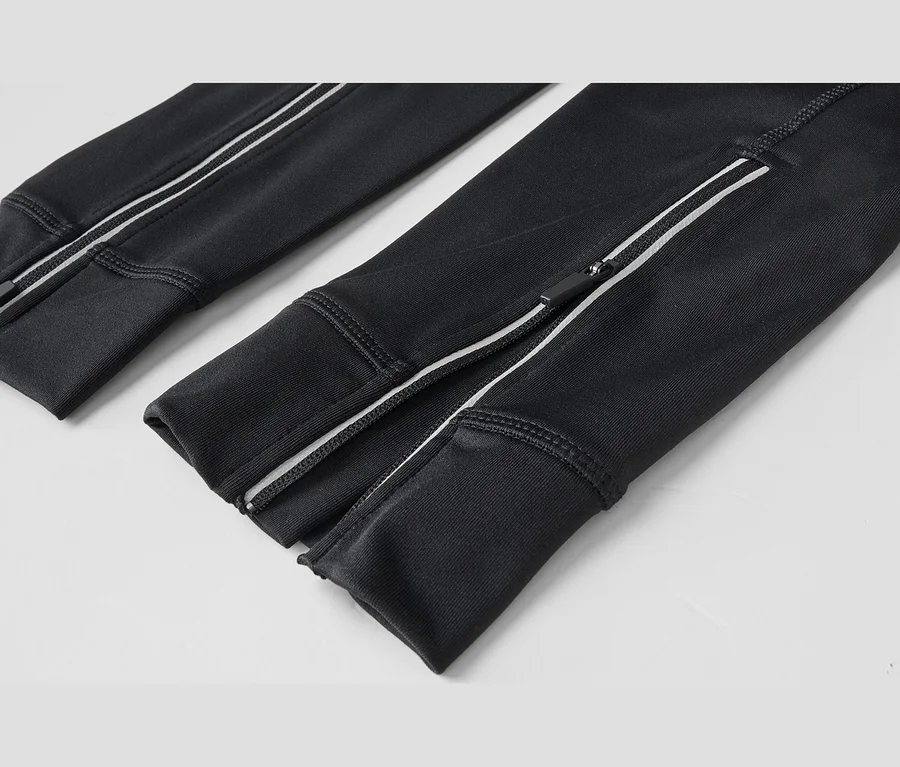 Gros plan sur la partie inférieure d'un pantalon noir, montrant des rayures blanches et des fermetures éclair aux chevilles.