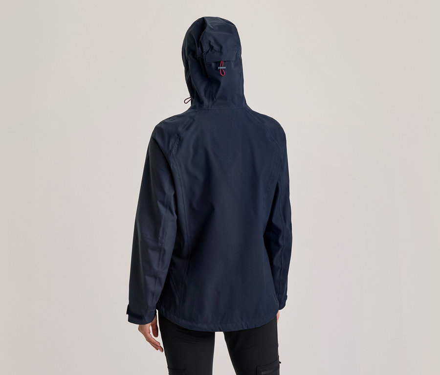 Personne vue de dos portant une veste à capuche bleu foncé avec un détail rouge sur la capuche et un pantalon noir.
