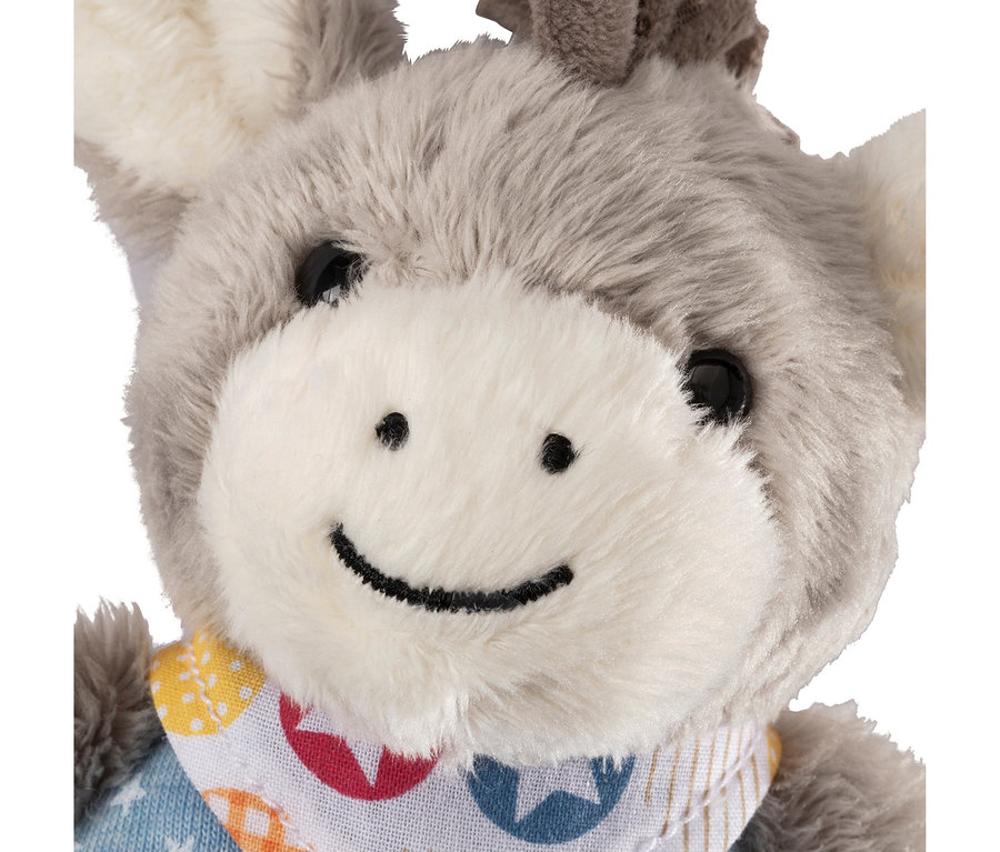 Gros plan d'un âne en peluche avec de la fourrure grise, un museau blanc, des yeux noirs et un sourire brodé. Il porte un bavoir coloré avec des étoiles et des cercles.