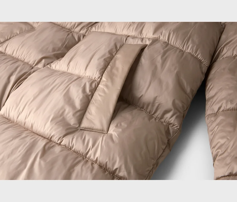 Gros plan d'une doudoune matelassée beige avec un rabat de poche visible.