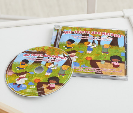 Sur une table blanche se trouvent un CD « Wir feiern den Herbst! » et un jouet en bois.
