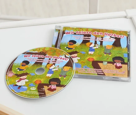 Sur une table blanche se trouvent un CD « Wir feiern den Herbst! » et un jouet en bois.