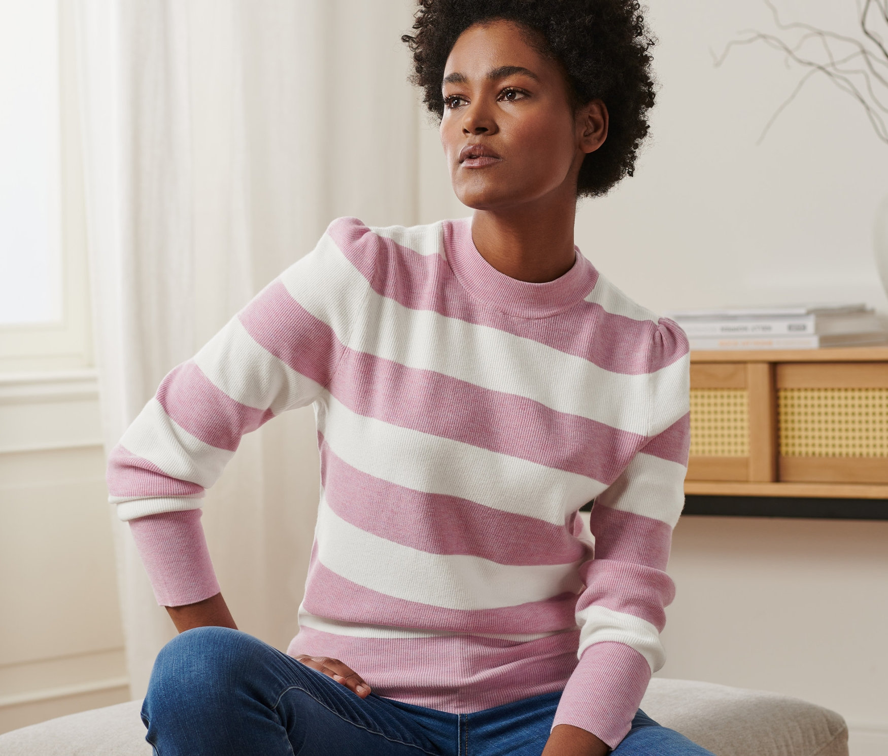 Femme assise portant un pull à manches bouffantes et un jean.