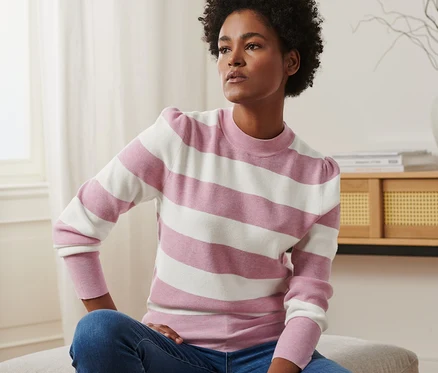 Femme assise portant un pull à manches bouffantes et un jean.