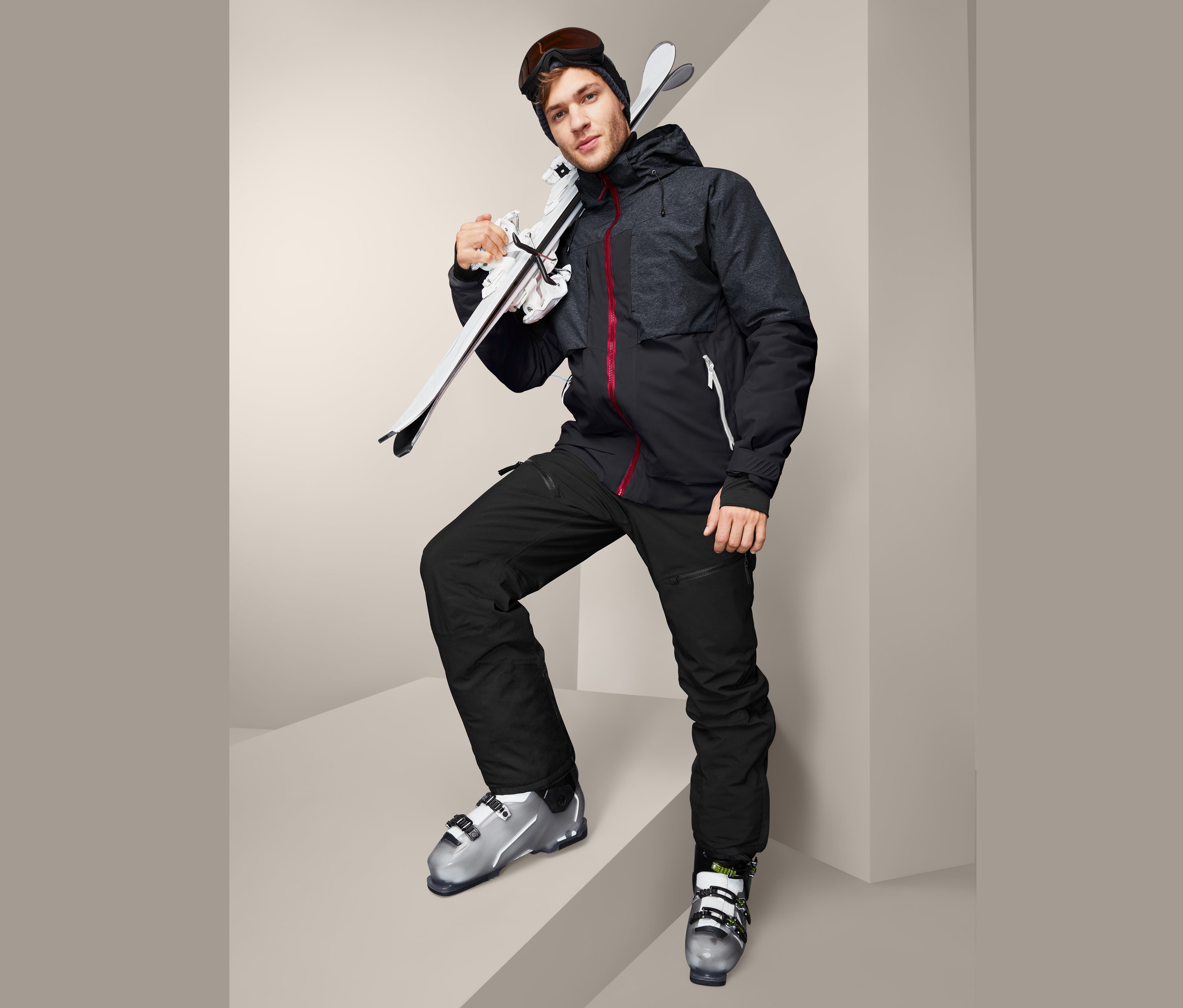 Homme en veste de ski « High-End » avec des skis et des chaussures de ski.