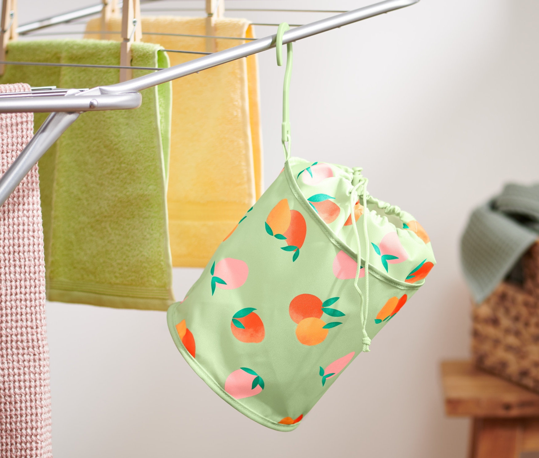 Un sac à pinces à linge est suspendu à un étendoir avec des serviettes.