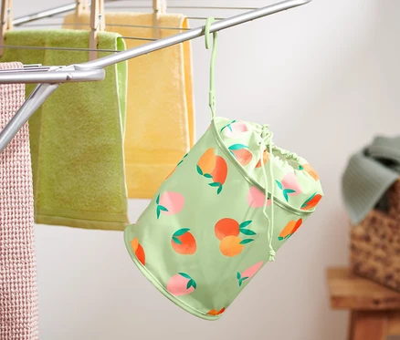 Un sac à pinces à linge est suspendu à un étendoir avec des serviettes.