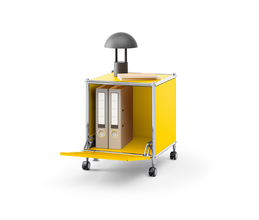 Table d’appoint en métal jaune « CN3 » avec abattant, sur laquelle reposent une lampe et un livre. Deux classeurs sont à l’intérieur de la table.