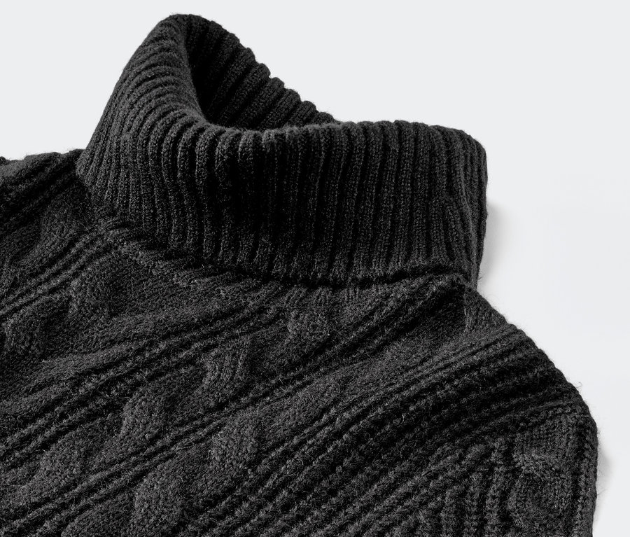 Gros plan d'un pull long en maille noire avec des torsades et un col roulé.