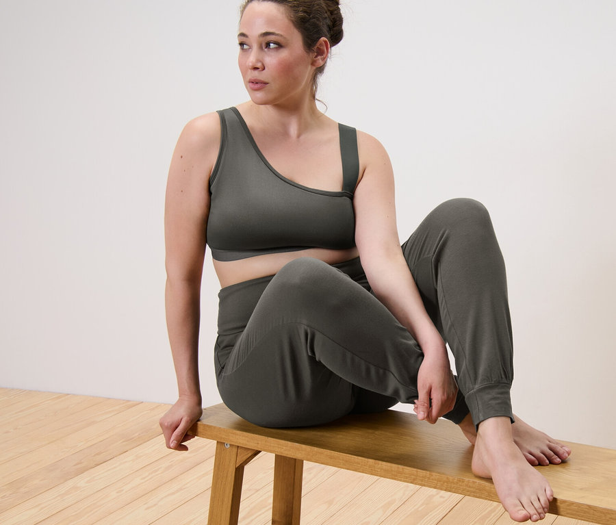Femme assise sur un banc en brassière de sport et pantalon de yoga.