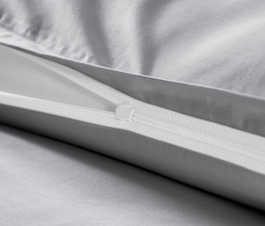 Gros plan d'une parure de lit en satin de coton grise avec fermeture éclair.