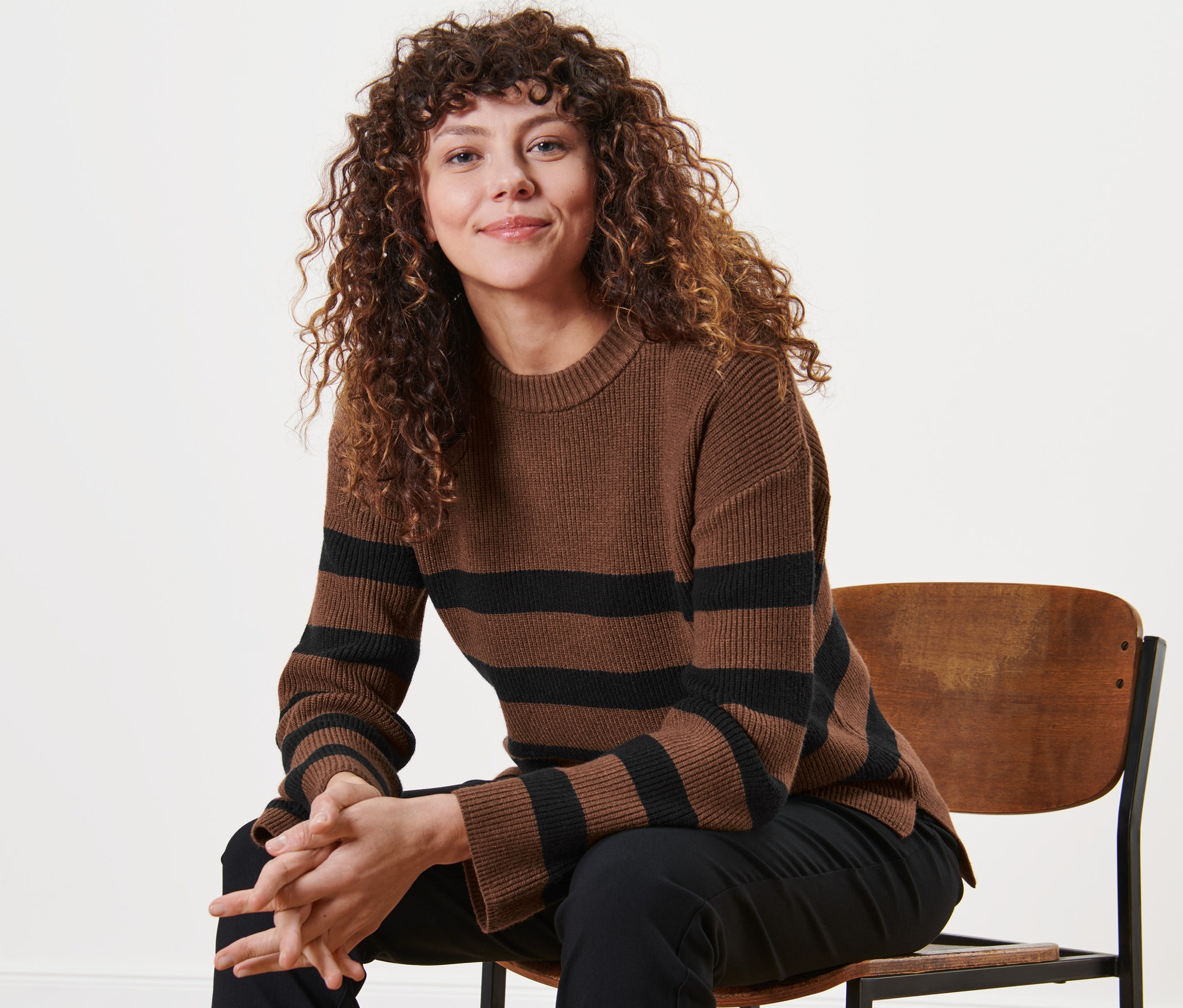 Une femme assise sur une chaise portant un pull en maille à rayures.