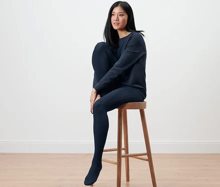 Une femme est assise sur un tabouret et porte des collants fins à motifs.