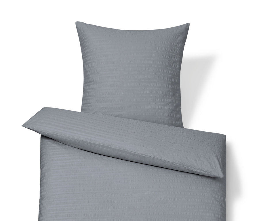 Une parure de lit en seersucker grise de taille standard et grande taille est disposée sur un fond blanc.