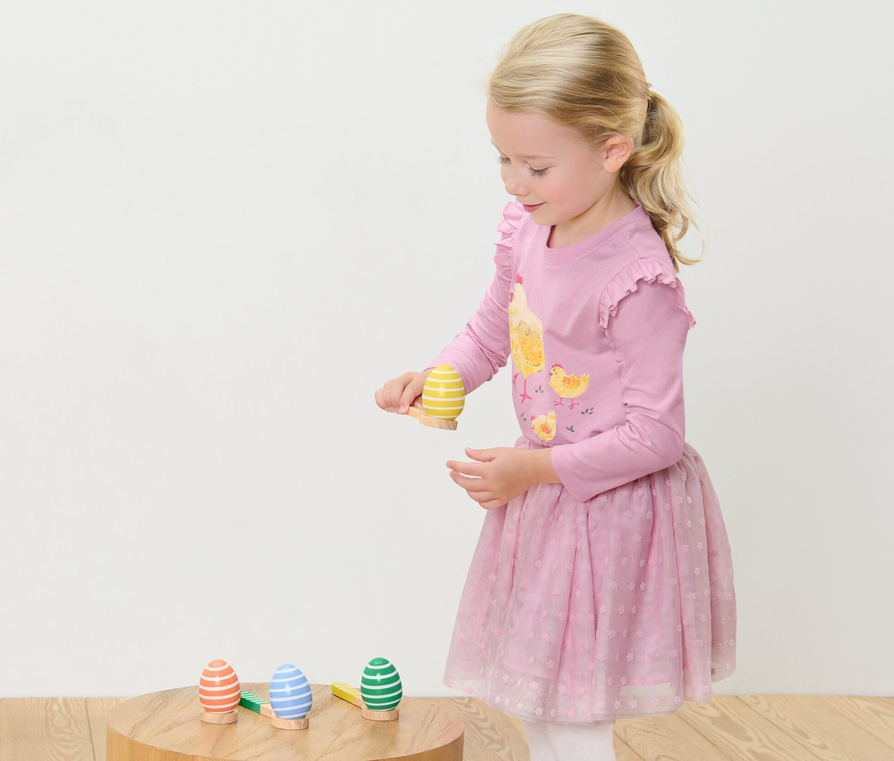 Une fille joue au Jeu de course à l’œuf. Elle se tient debout et se concentre sur l'équilibre d'un œuf sur une cuillère.