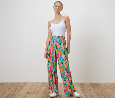 Une femme debout porte un pantalon palazzo imprimé multicolore.