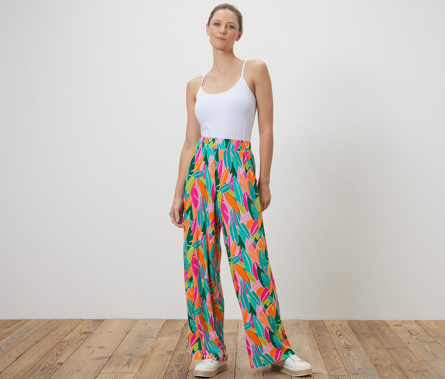Une femme debout porte un pantalon palazzo imprimé multicolore.