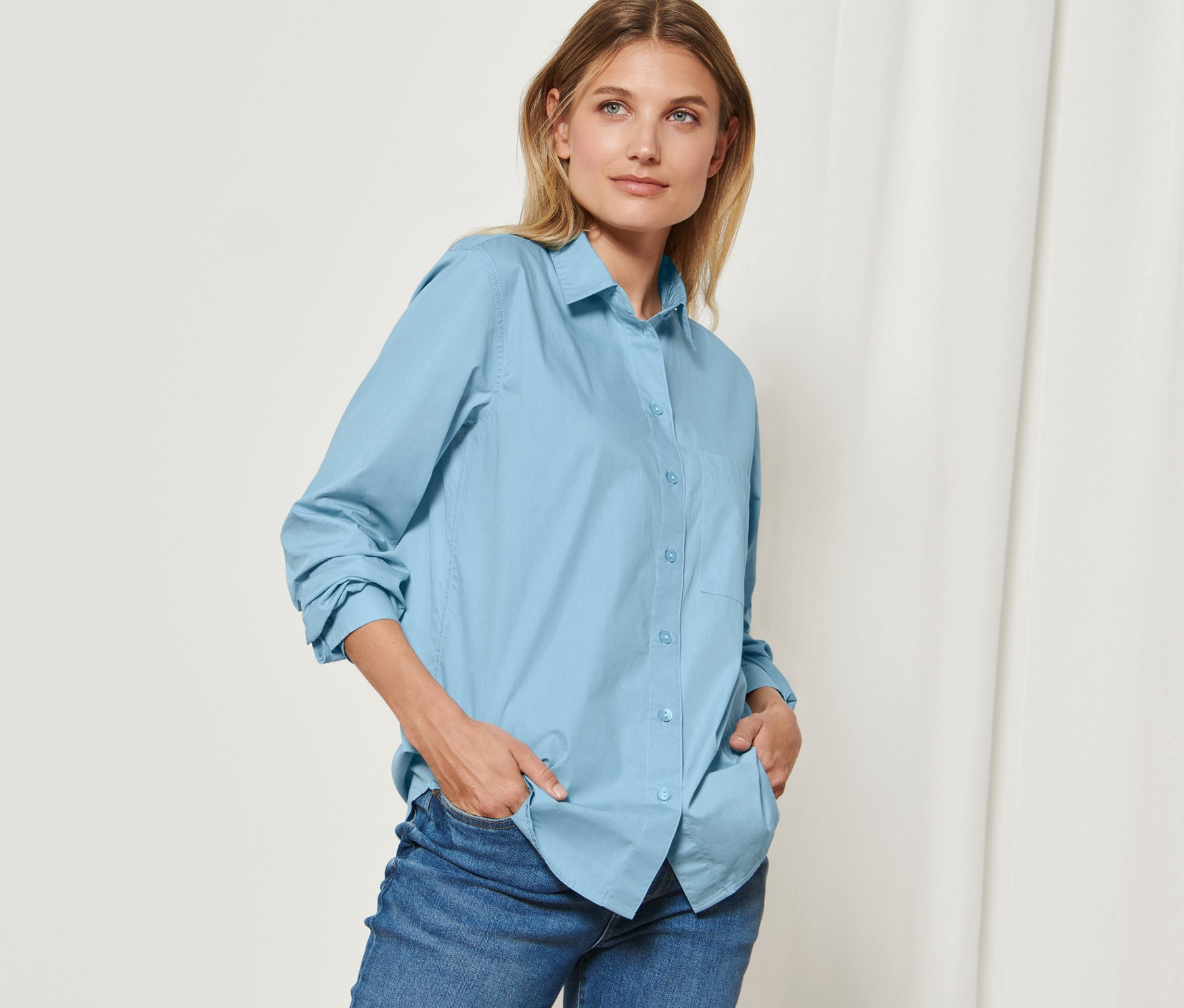 Femme posant en chemisier bleu clair.