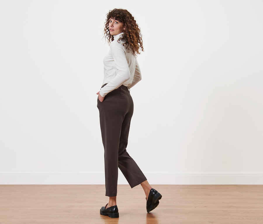 Femme regardant par-dessus son épaule et posant en pantalon tissé à pinces.