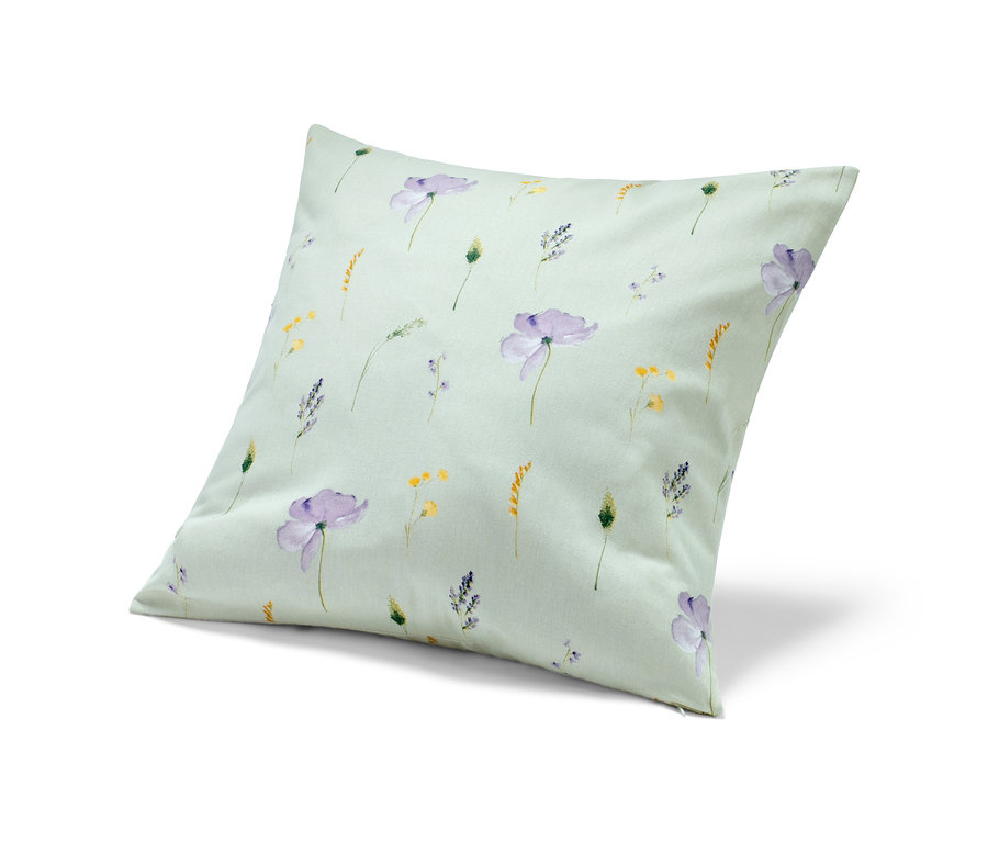 Une housse de coussin décorative avec un motif de fleurs violettes et jaunes sur un fond vert clair.