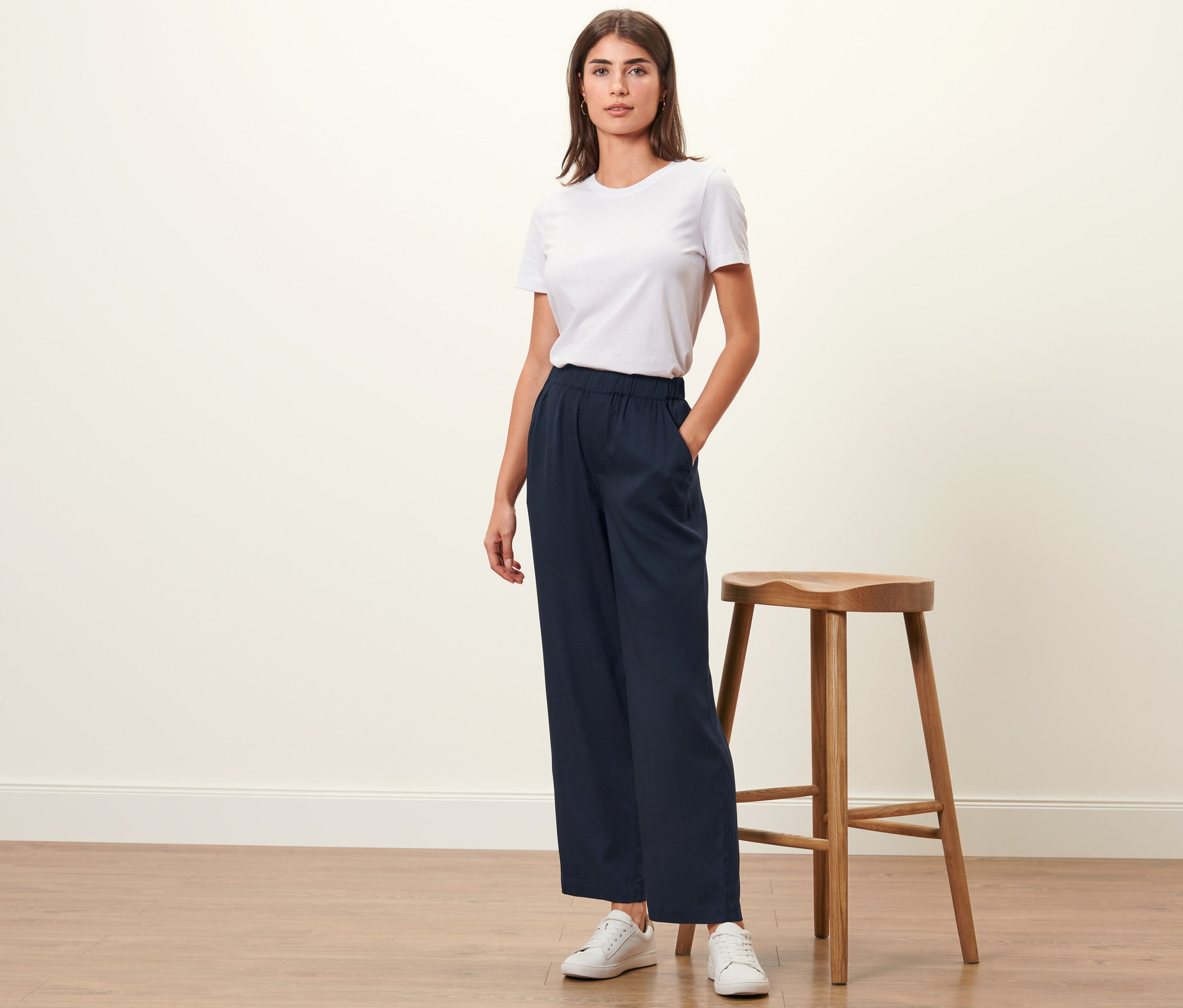 Femme posant en pantalon tissé bleu foncé et t-shirt blanc.