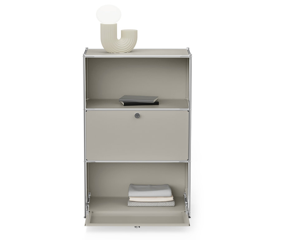 Une armoire grise avec un cadre argenté a une étagère inférieure ouverte avec des vêtements pliés et une étagère supérieure avec des livres.