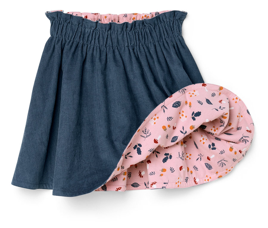 Gros plan sur une jupe réversible en velours pour enfant, un côté est bleu, l'autre rose avec un imprimé.