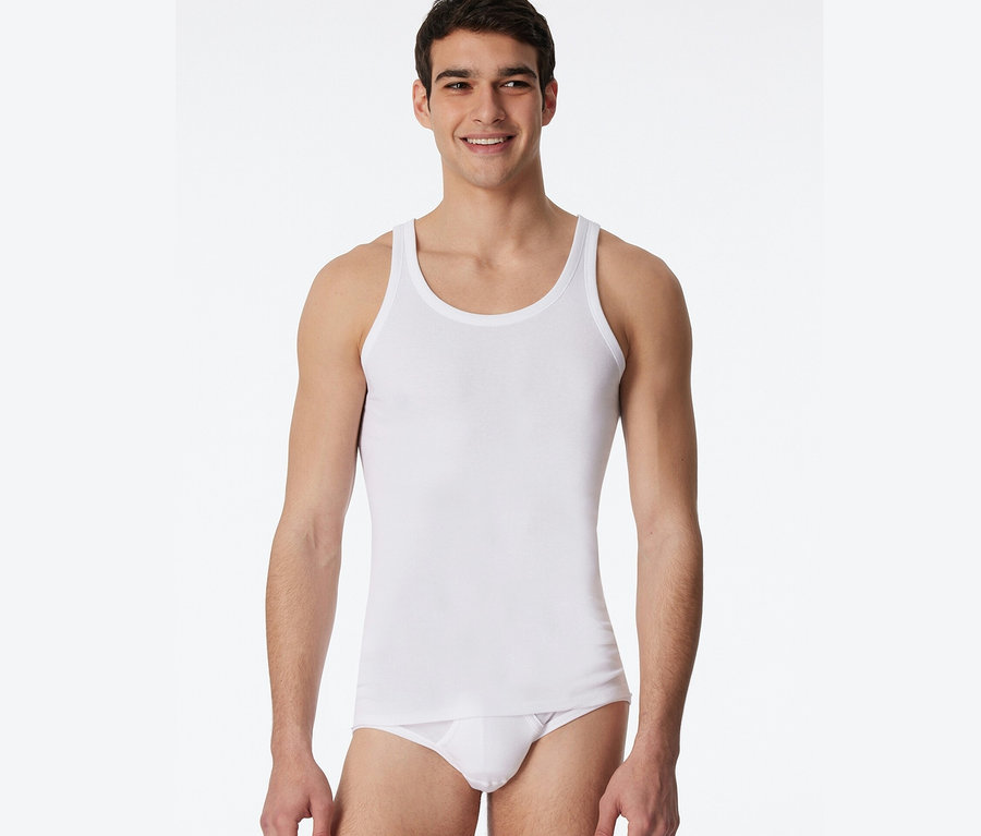 Un homme portant 2 maillots de corps blancs SCHIESSER en maille côtelée fine.