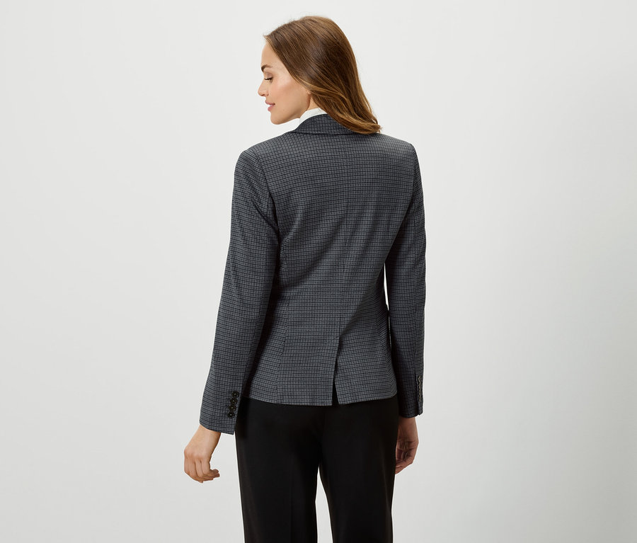 Une femme porte un blazer à carreaux et un pantalon noir.