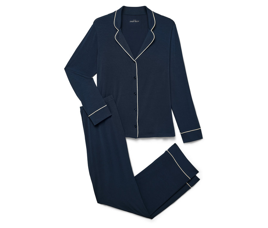 Pyjama bleu marine avec haut à manches longues et pantalon avec passepoil blanc sur fond blanc.