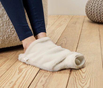 Pieds en leggings bleus insérés dans une couverture de bouillotte moelleuse de couleur crème.